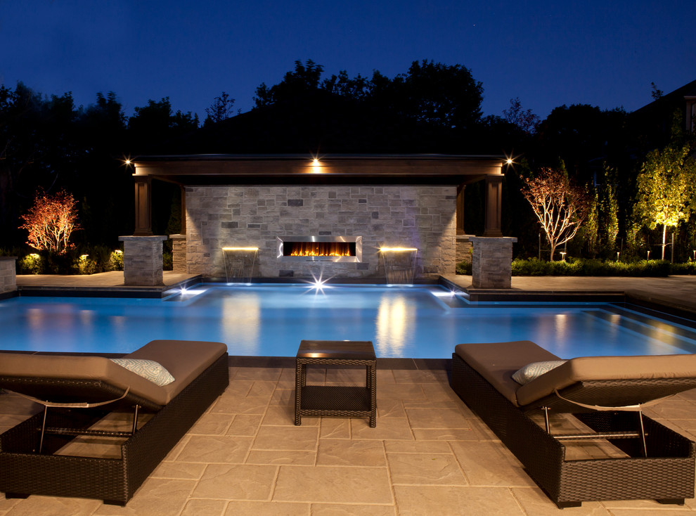 Diseño de piscina con fuente alargada moderna grande rectangular en patio trasero con suelo de hormigón estampado
