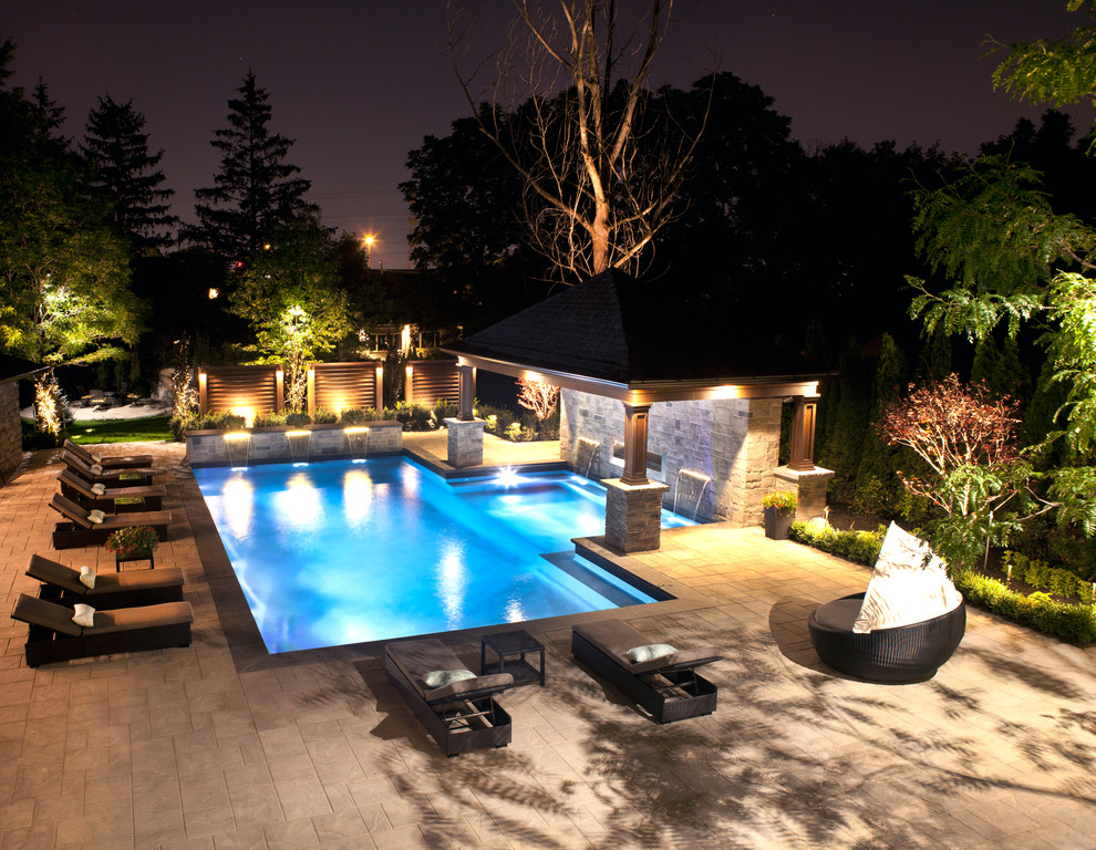 Imagen de piscina con fuente alargada moderna grande rectangular en patio trasero con suelo de hormigón estampado