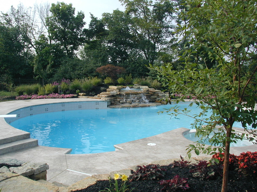 Imagen de piscinas y jacuzzis tradicionales grandes a medida en patio trasero con adoquines de hormigón