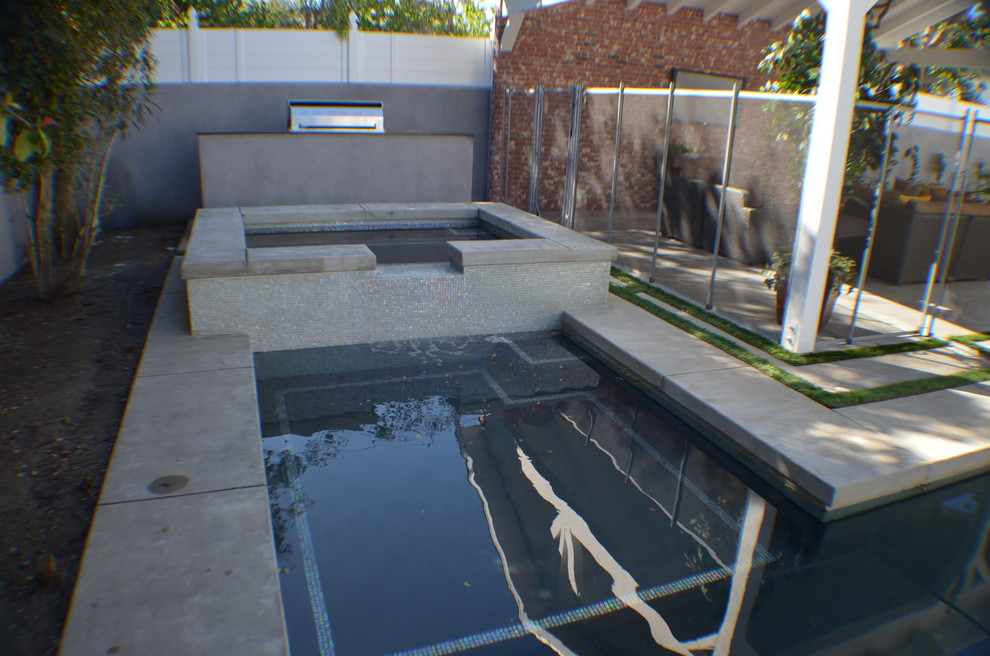Diseño de piscinas y jacuzzis naturales tradicionales de tamaño medio rectangulares en patio trasero con losas de hormigón