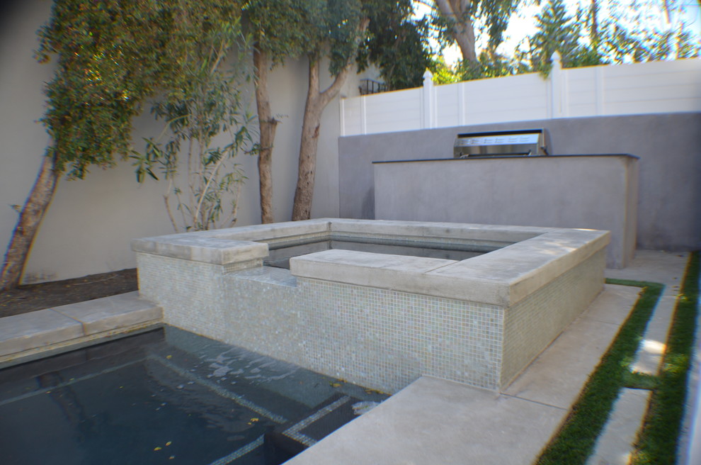 На фото: естественный, прямоугольный бассейн среднего размера на заднем дворе в классическом стиле с джакузи и мощением тротуарной плиткой с