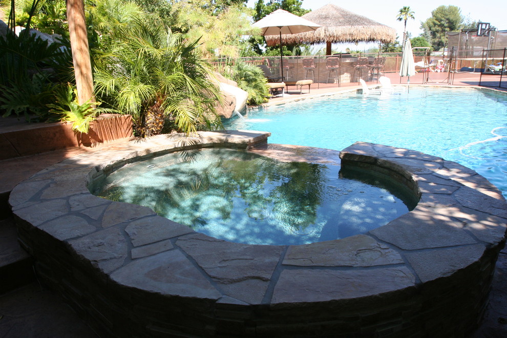 Photo of a medium sized world-inspired back custom shaped lengths swimming pool in Los Angeles with a water slide and natural stone paving.