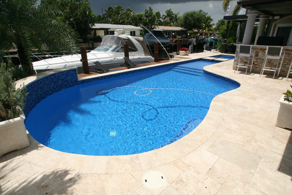 Diseño de piscina con fuente mediterránea de tamaño medio a medida en patio trasero con adoquines de piedra natural