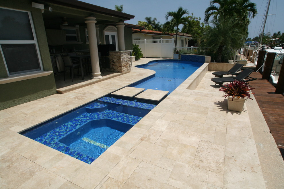 Réalisation d'une piscine arrière méditerranéenne de taille moyenne et sur mesure avec un point d'eau et des pavés en pierre naturelle.
