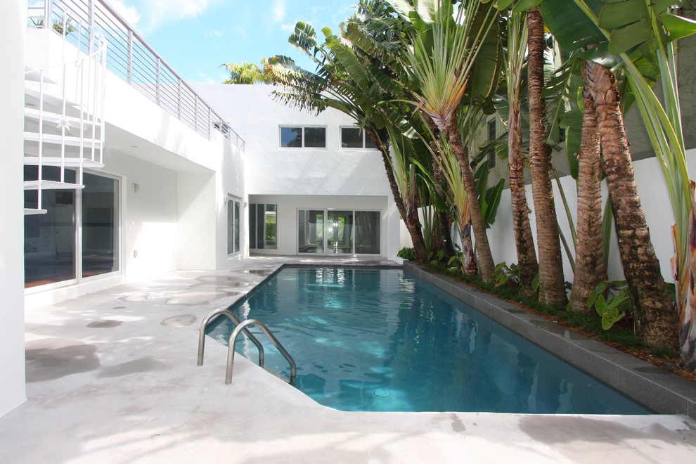Ejemplo de piscina minimalista a medida en patio lateral con losas de hormigón