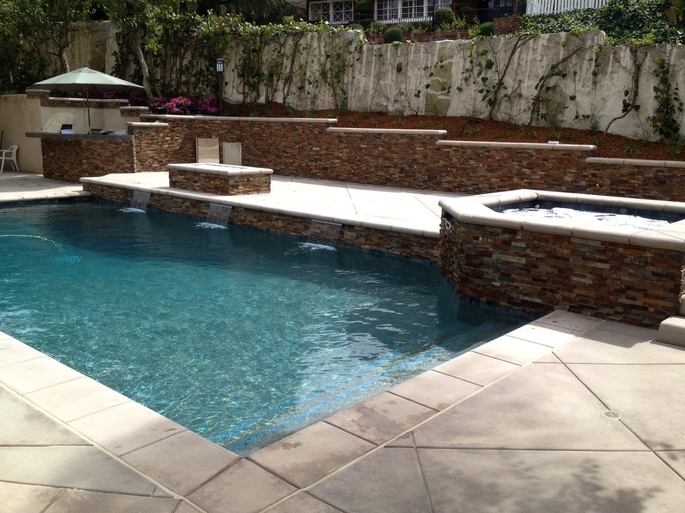 Ejemplo de piscina con fuente natural clásica renovada de tamaño medio rectangular en patio trasero con suelo de hormigón estampado
