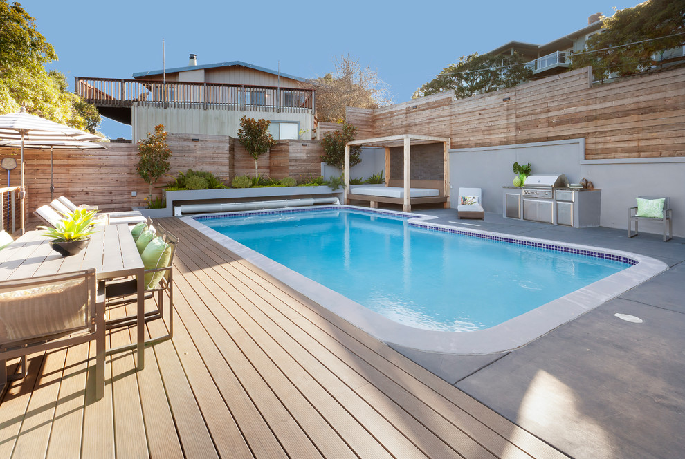 Example of a transitional rectangular pool design in Other with decking