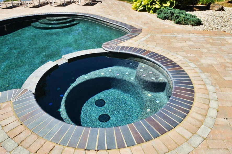 Hot tub - large modern backyard stamped concrete and custom-shaped hot tub idea in New York