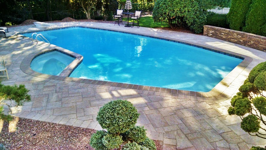 Пример оригинального дизайна: большой бассейн произвольной формы на заднем дворе в стиле модернизм с джакузи и покрытием из декоративного бетона