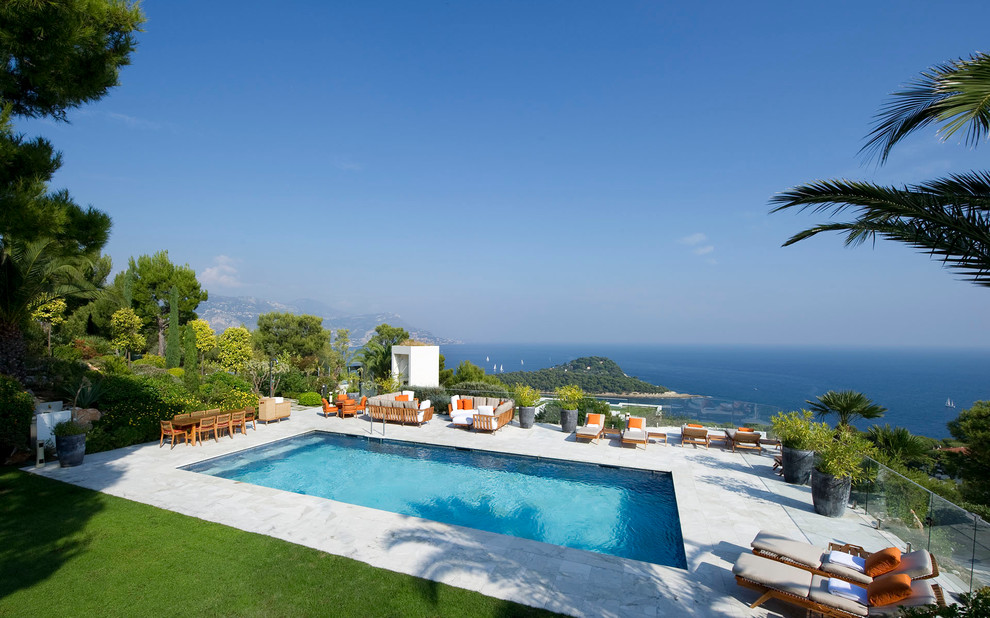 Ejemplo de piscina alargada tropical grande rectangular en patio trasero con losas de hormigón