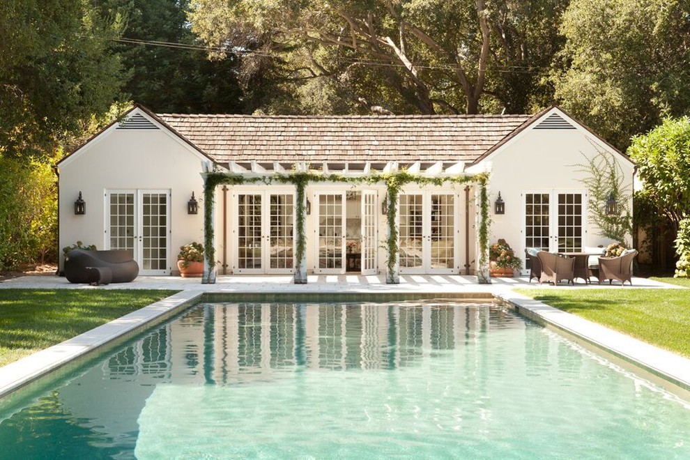Modelo de casa de la piscina y piscina alargada clásica grande rectangular en patio trasero con adoquines de hormigón