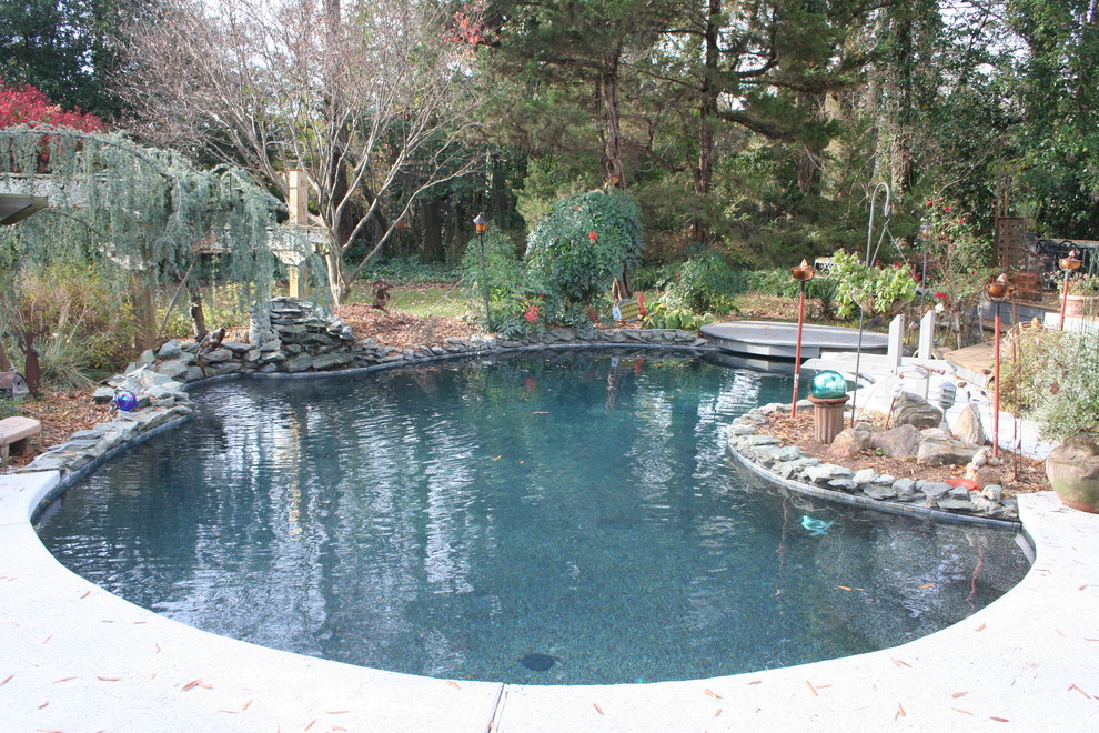 Стильный дизайн: естественный бассейн среднего размера, в форме фасоли на заднем дворе в стиле фьюжн с фонтаном и покрытием из бетонных плит - последний тренд