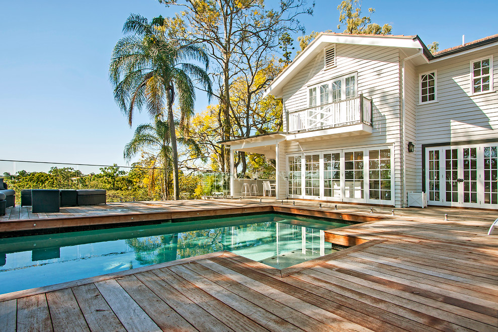 Cette photo montre une piscine arrière chic de taille moyenne et rectangle avec une terrasse en bois.