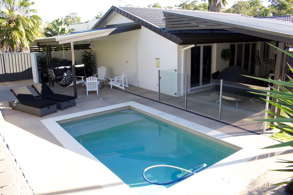 Modelo de piscina exótica pequeña rectangular en patio trasero con adoquines de hormigón