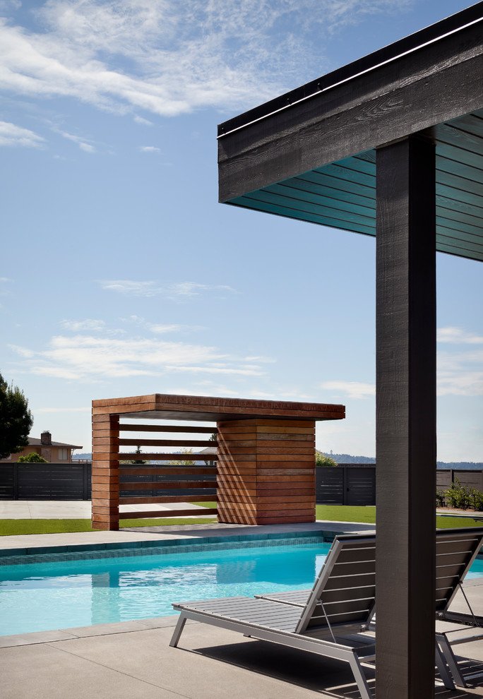 Пример оригинального дизайна: бассейн на заднем дворе в современном стиле с домиком у бассейна и мощением тротуарной плиткой