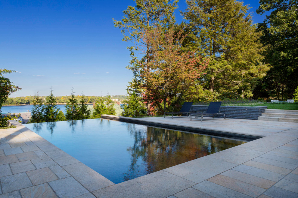 Foto de piscina con fuente infinita actual grande rectangular en patio trasero con adoquines de piedra natural
