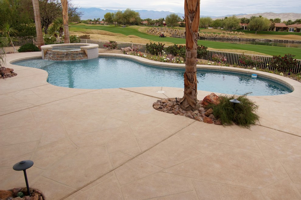 Ejemplo de piscinas y jacuzzis alargados tropicales grandes tipo riñón en patio trasero con adoquines de piedra natural