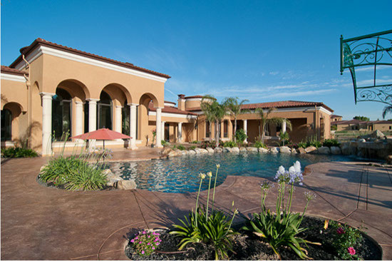 Immagine di una grande piscina monocorsia mediterranea personalizzata dietro casa con lastre di cemento e una vasca idromassaggio