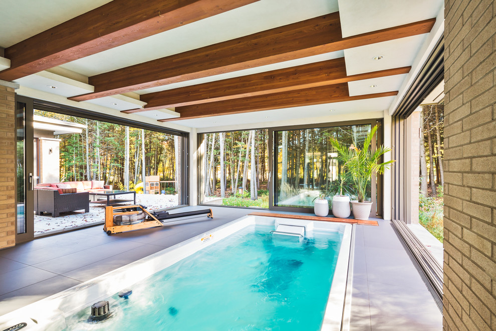 Ispirazione per una piscina minimal rettangolare di medie dimensioni e dietro casa con una vasca idromassaggio e piastrelle