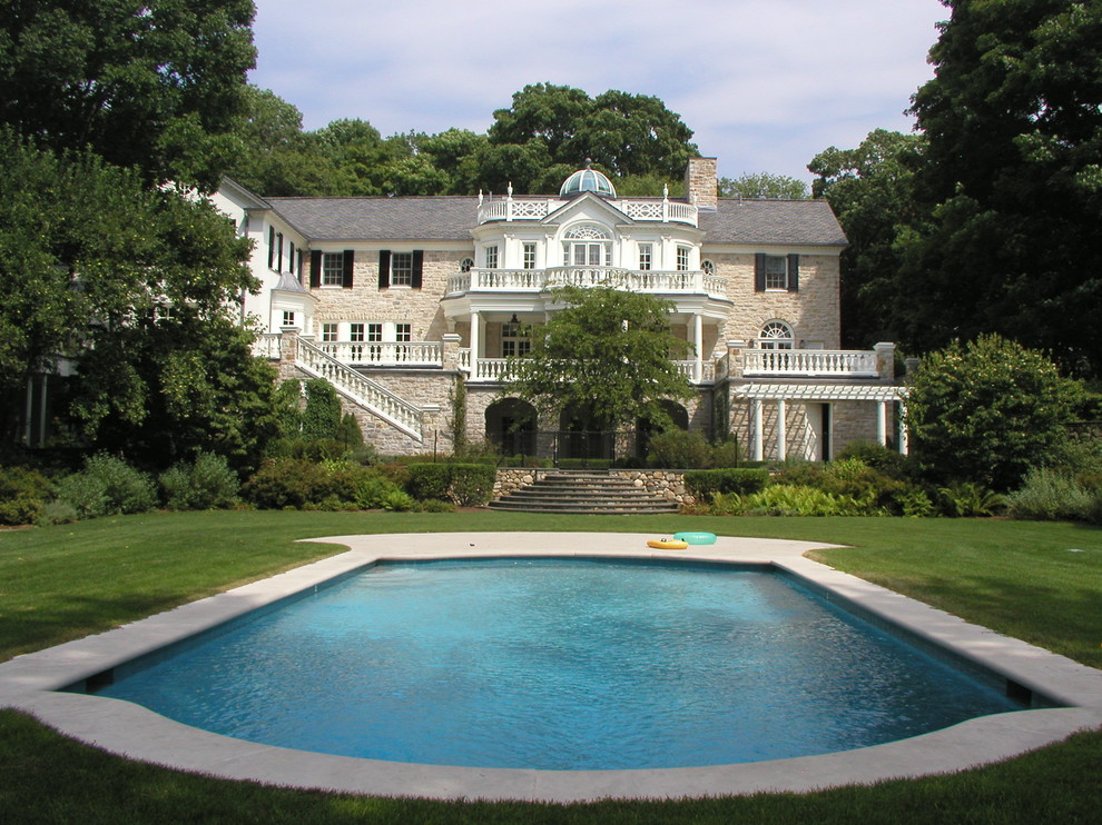 Inredning av en klassisk anpassad pool på baksidan av huset, med naturstensplattor