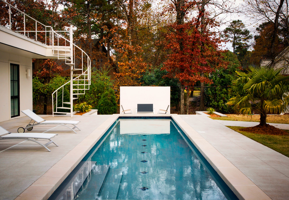 На фото: большой спортивный, прямоугольный бассейн на заднем дворе в современном стиле с мощением тротуарной плиткой
