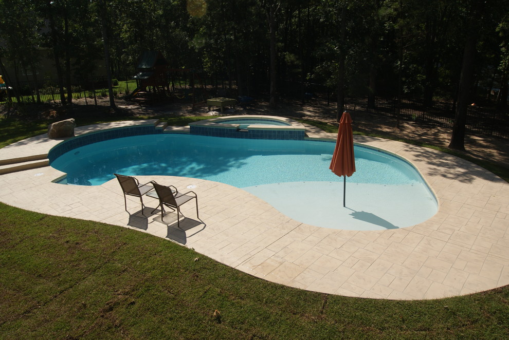 Esempio di una piscina monocorsia design a "C" dietro casa con una vasca idromassaggio