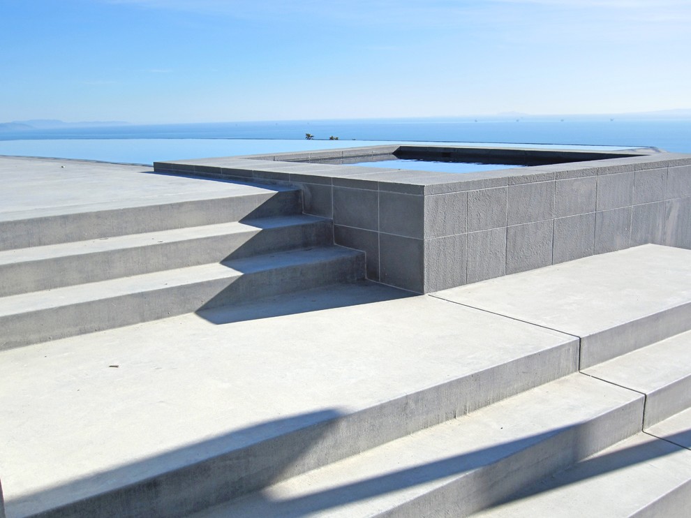 Пример оригинального дизайна: большой прямоугольный бассейн-инфинити на заднем дворе в современном стиле с джакузи и покрытием из бетонных плит