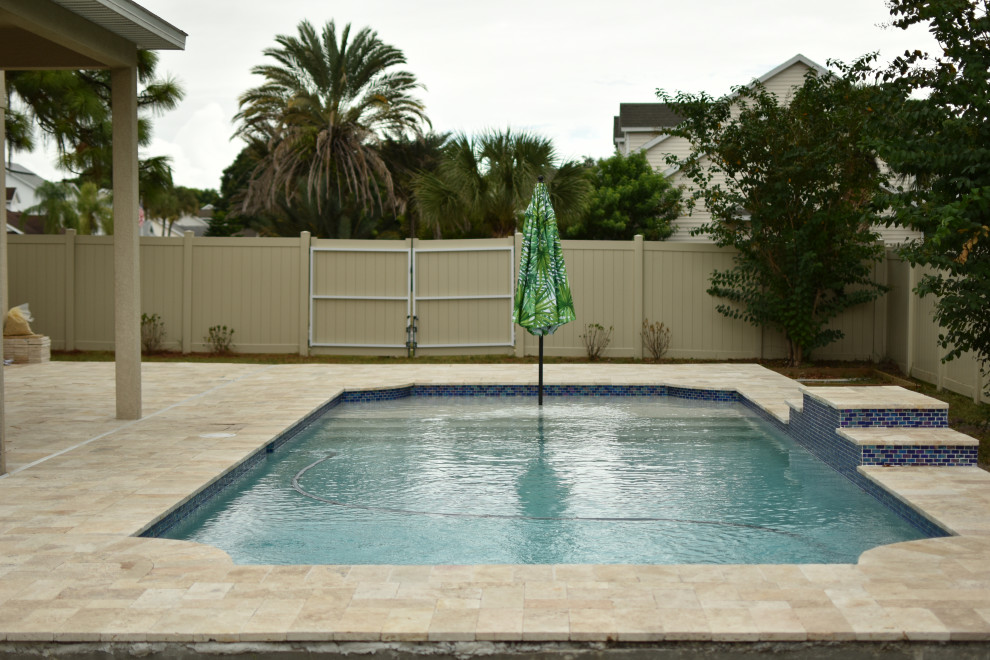 Imagen de piscina actual pequeña rectangular en patio trasero con adoquines de piedra natural