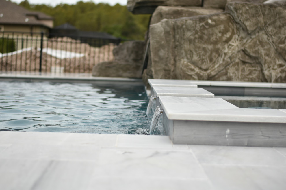 Идея дизайна: большой бассейн произвольной формы на заднем дворе в современном стиле с водной горкой и покрытием из каменной брусчатки