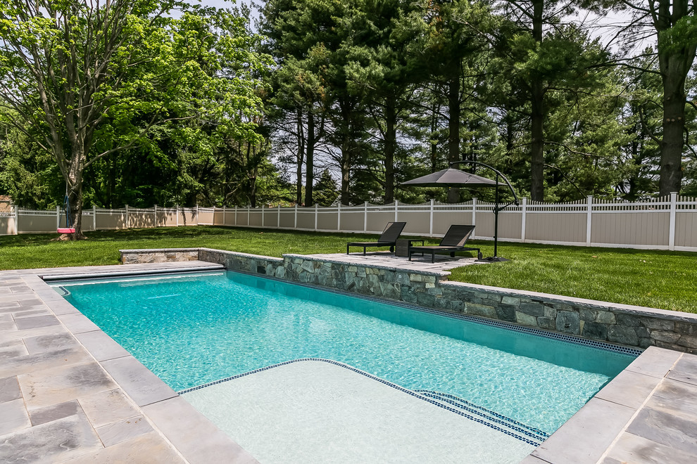 Immagine di una piscina chic rettangolare di medie dimensioni e dietro casa con pavimentazioni in pietra naturale