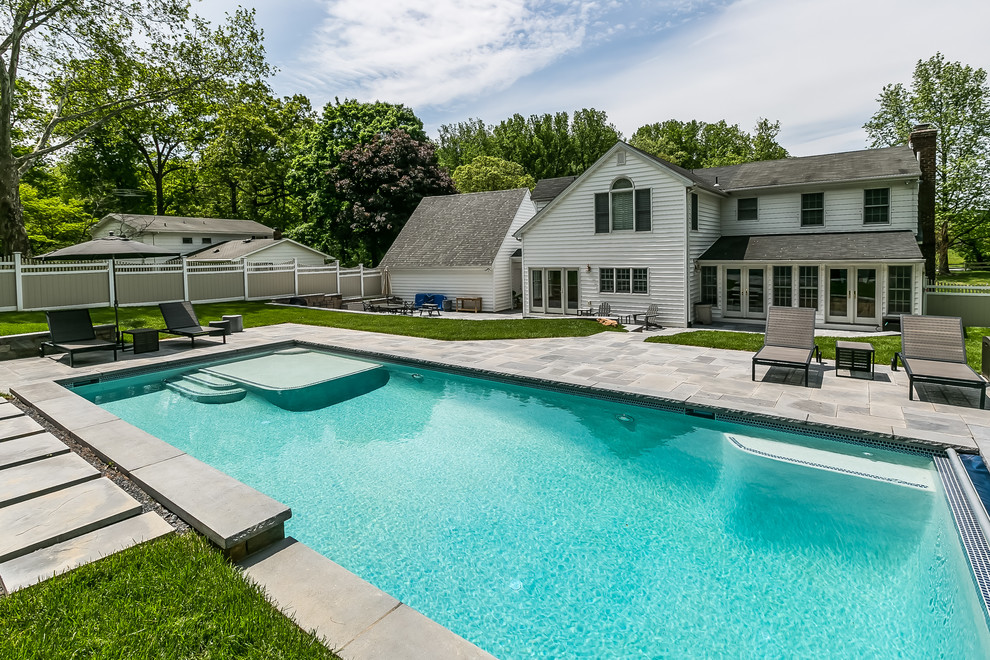 Immagine di una piscina monocorsia classica rettangolare di medie dimensioni e dietro casa con pavimentazioni in pietra naturale