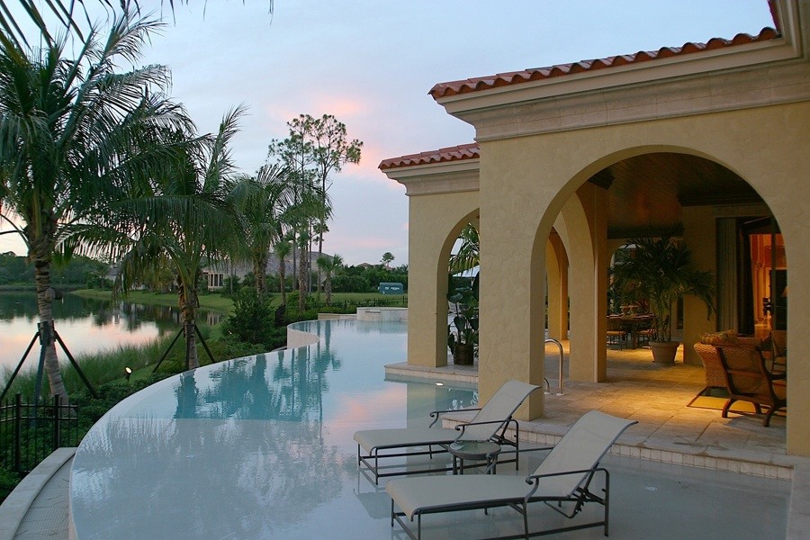 This is an example of a mediterranean back custom shaped infinity swimming pool in Miami with concrete paving.