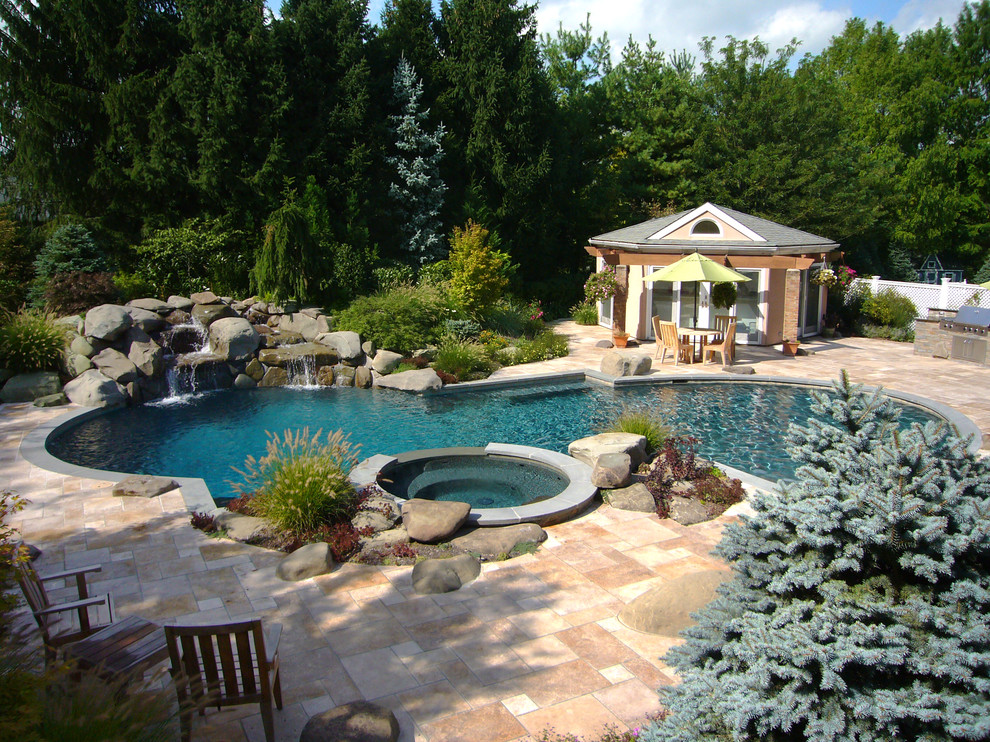 На фото: естественный бассейн произвольной формы на заднем дворе в классическом стиле с покрытием из каменной брусчатки и джакузи
