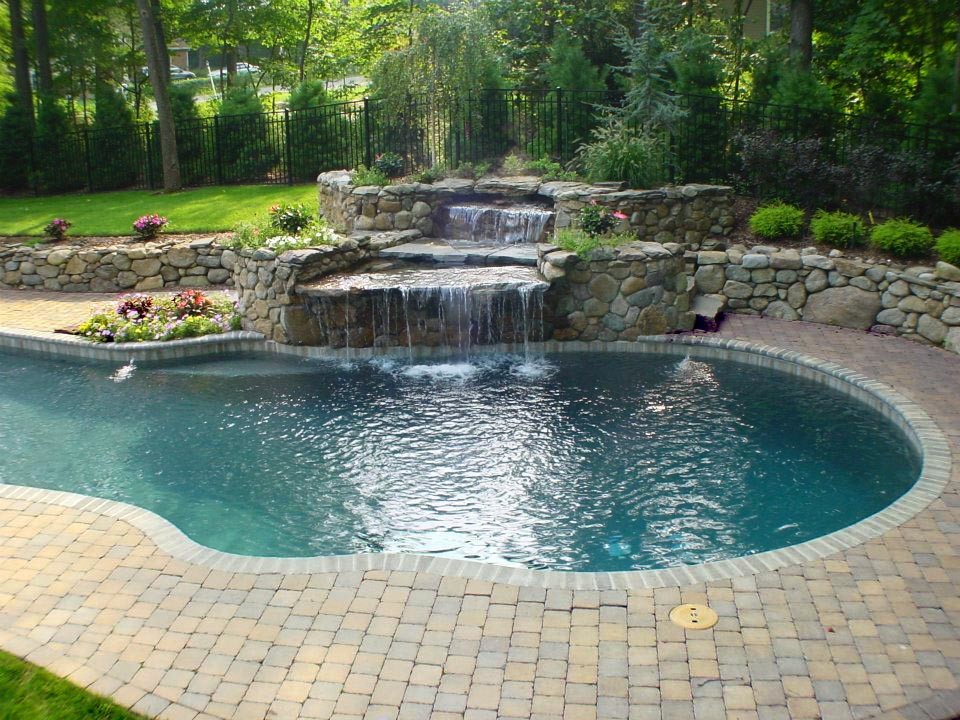 Photo of a large classic back custom shaped natural hot tub in New York with concrete paving.