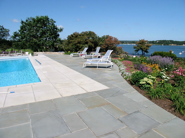 Inspiration for a large classic back rectangular natural swimming pool in Boston with natural stone paving.
