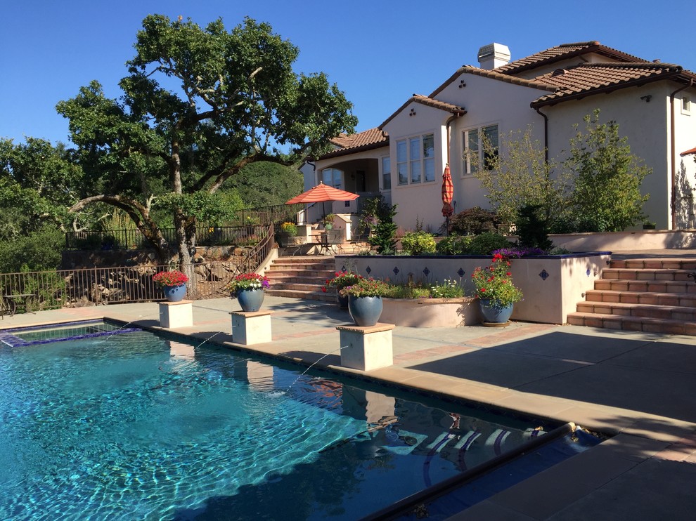 Modelo de piscinas y jacuzzis alargados de estilo americano extra grandes rectangulares en patio trasero con losas de hormigón