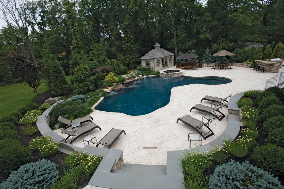 Esempio di un'ampia piscina naturale chic personalizzata dietro casa con fontane e pedane