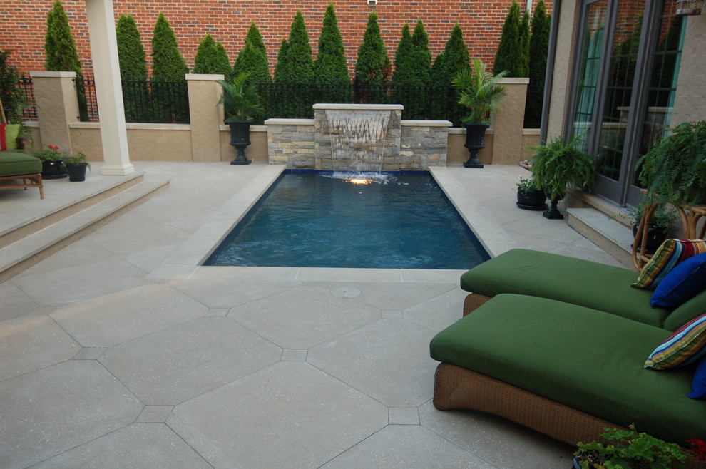 Imagen de piscina con fuente alargada de estilo americano pequeña rectangular en patio con adoquines de hormigón