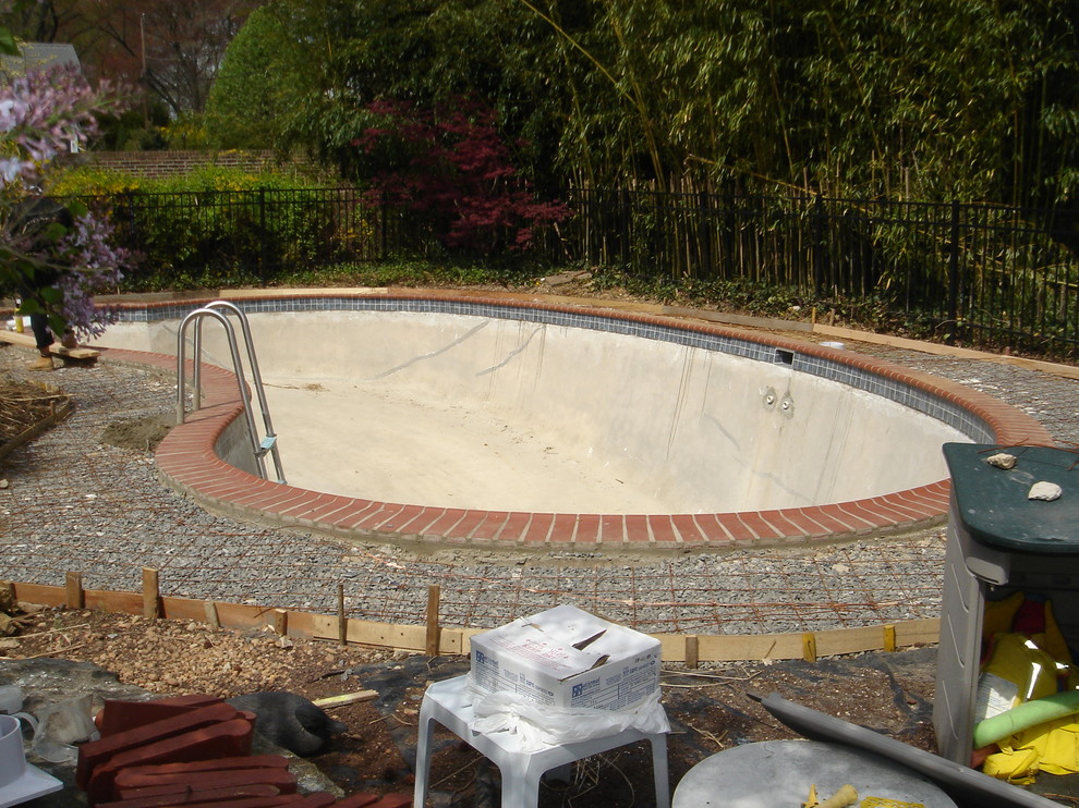 Immagine di una piscina naturale tradizionale a "C" dietro casa e di medie dimensioni con lastre di cemento