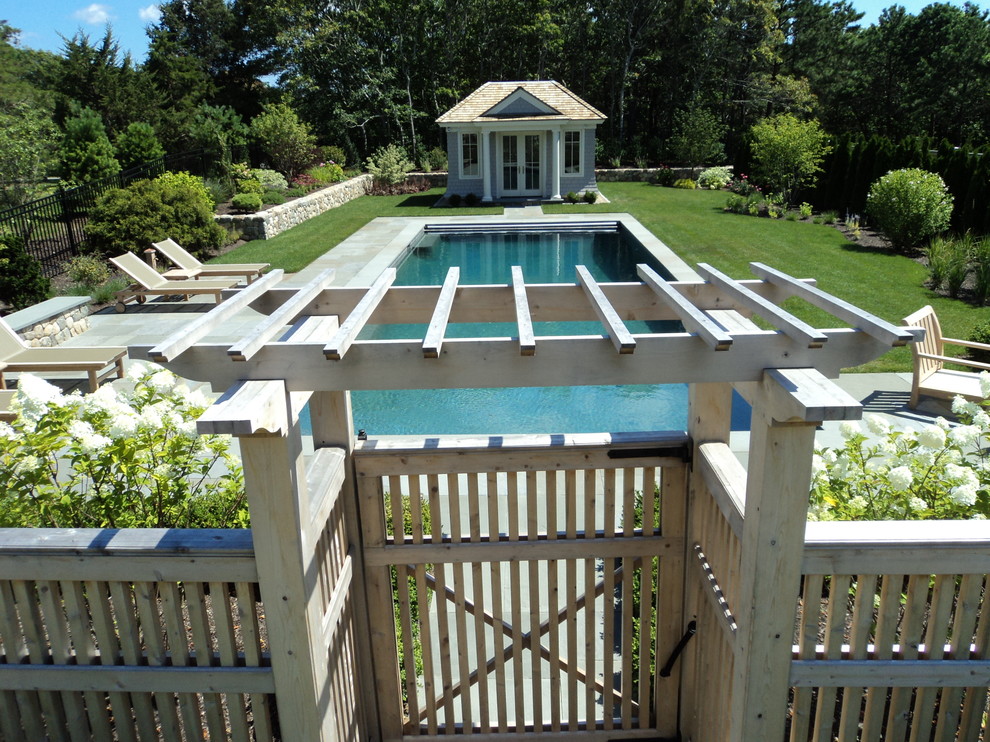 Imagen de piscina natural clásica grande rectangular en patio trasero con losas de hormigón