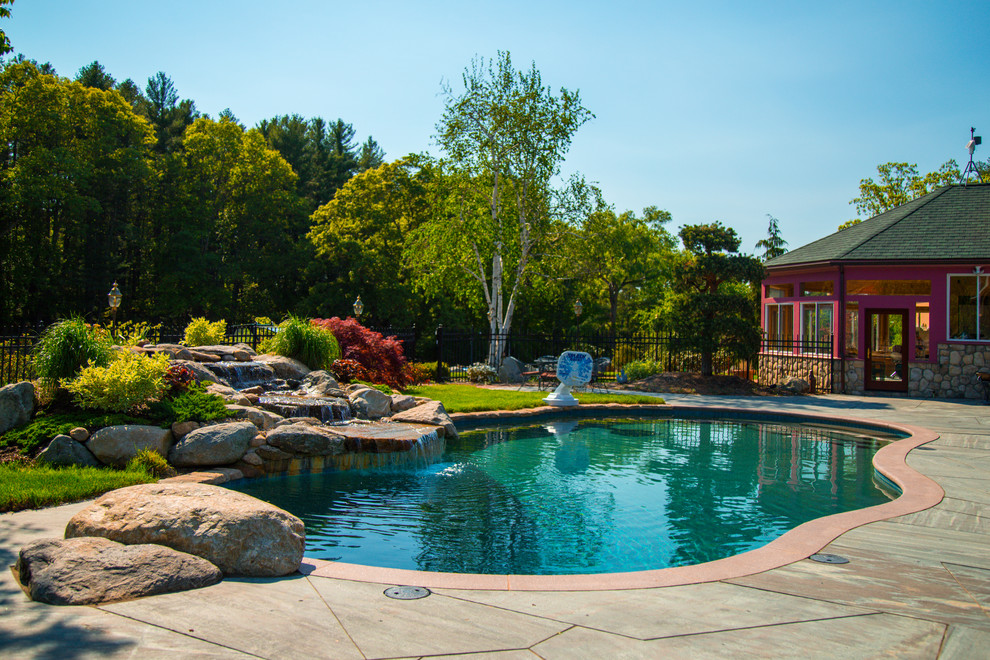 На фото: большой естественный бассейн произвольной формы на заднем дворе в стиле фьюжн с домиком у бассейна и покрытием из каменной брусчатки