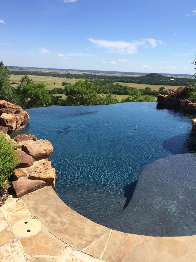 Großer Landhaus Infinity-Pool hinter dem Haus in Nierenform mit Natursteinplatten in Austin