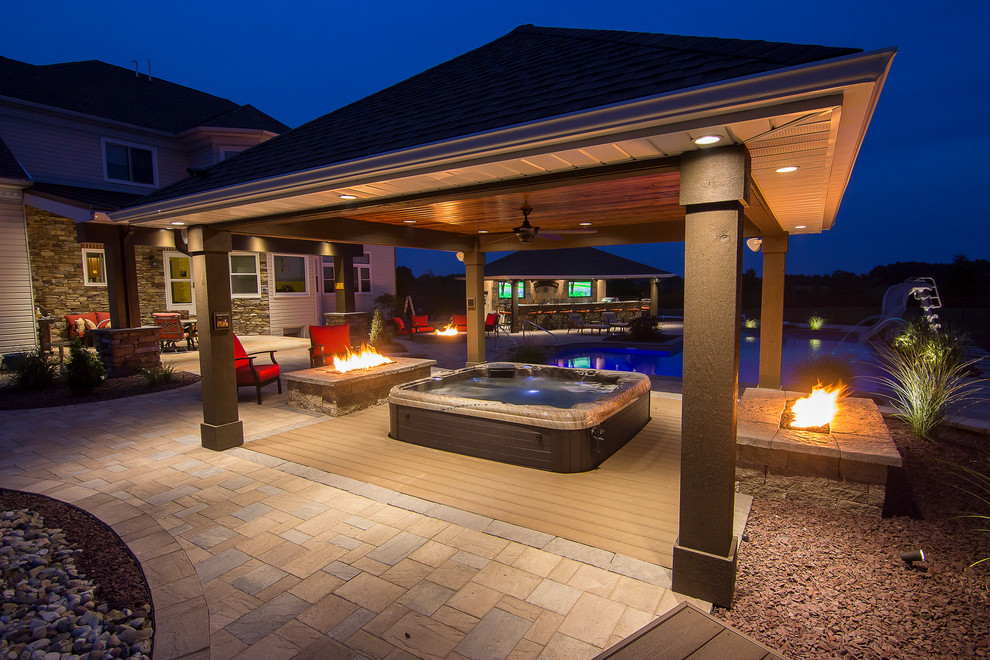 Diseño de piscinas y jacuzzis alargados actuales grandes en forma de L en patio trasero con adoquines de hormigón