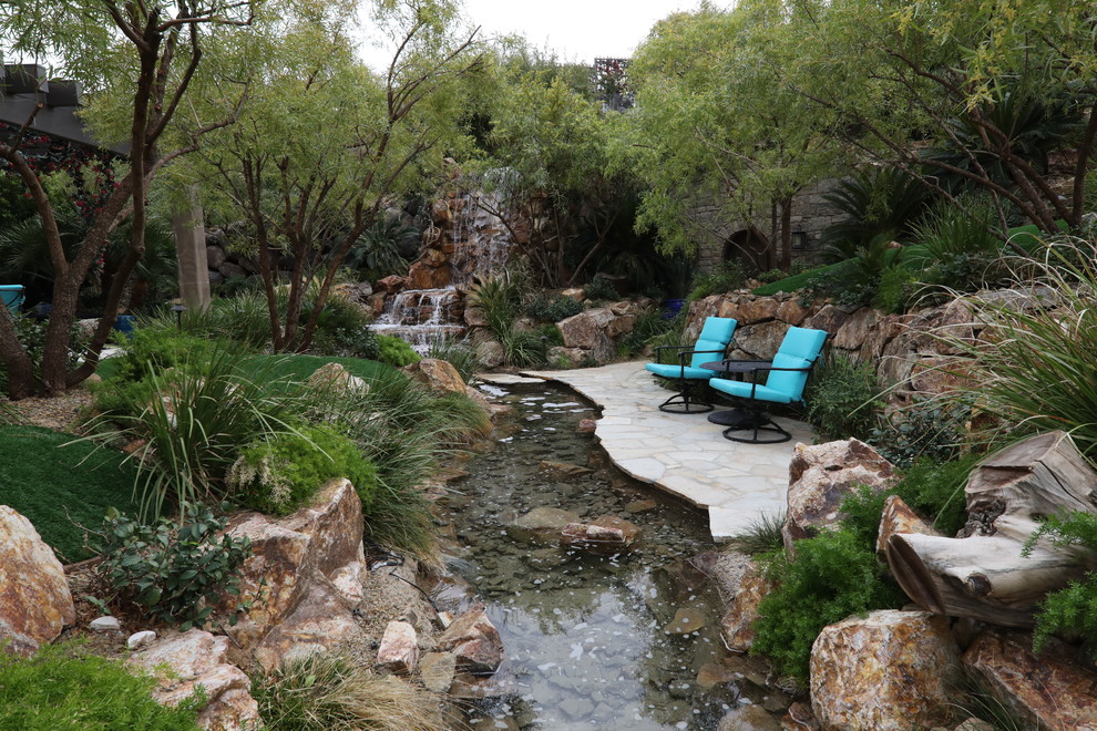 Idee per un'ampia piscina naturale tropicale personalizzata dietro casa con fontane e pavimentazioni in pietra naturale