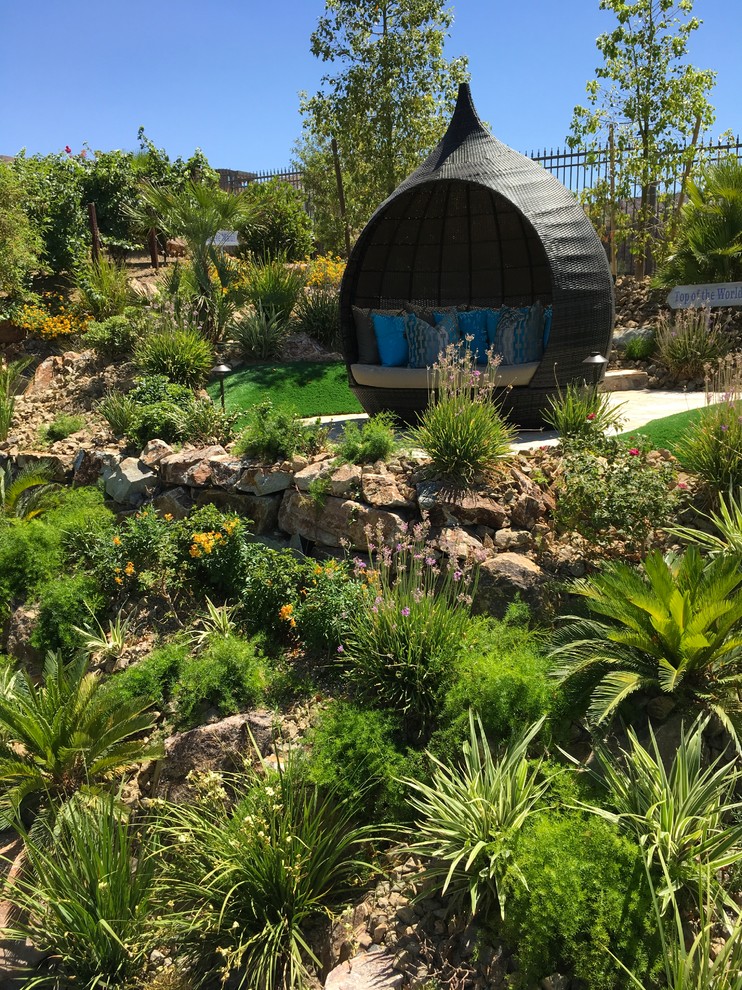 Foto di un'ampia piscina naturale tropicale personalizzata dietro casa con fontane e pavimentazioni in pietra naturale
