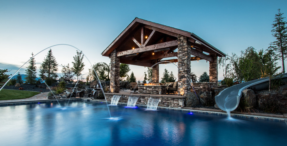 Diseño de piscina con tobogán rústica de tamaño medio rectangular en patio trasero con adoquines de hormigón