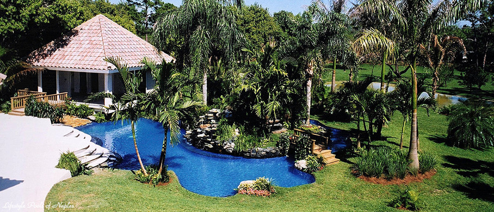 Immagine di un'ampia piscina naturale tropicale personalizzata dietro casa con una dépendance a bordo piscina