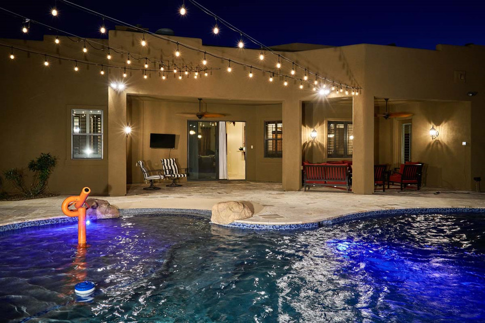 Diseño de piscina con tobogán natural exótica grande a medida en patio trasero con adoquines de piedra natural