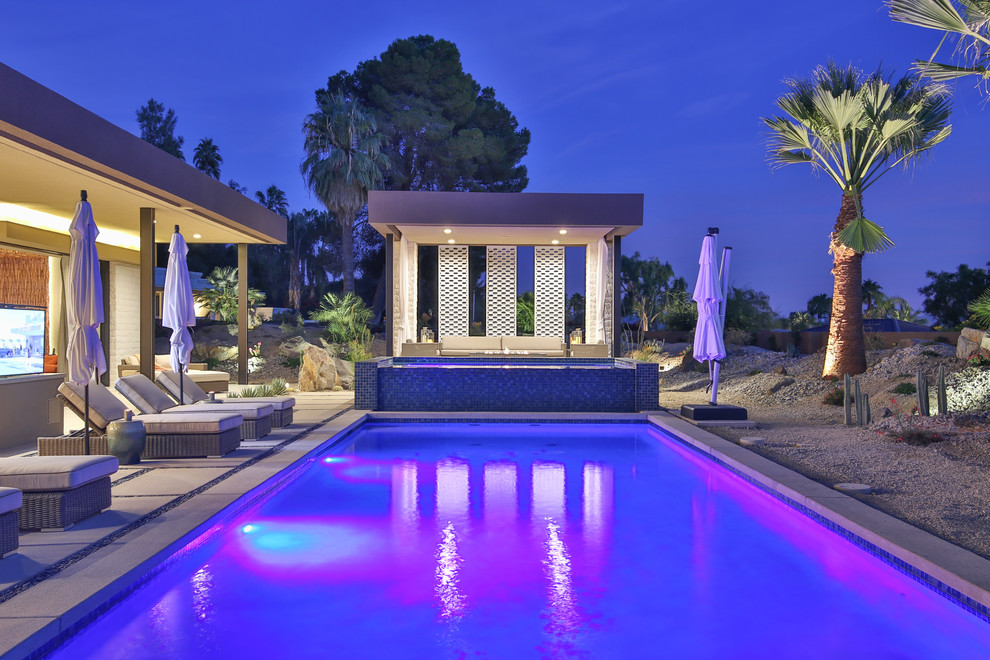 Ispirazione per un'ampia piscina monocorsia contemporanea rettangolare dietro casa con una vasca idromassaggio e lastre di cemento