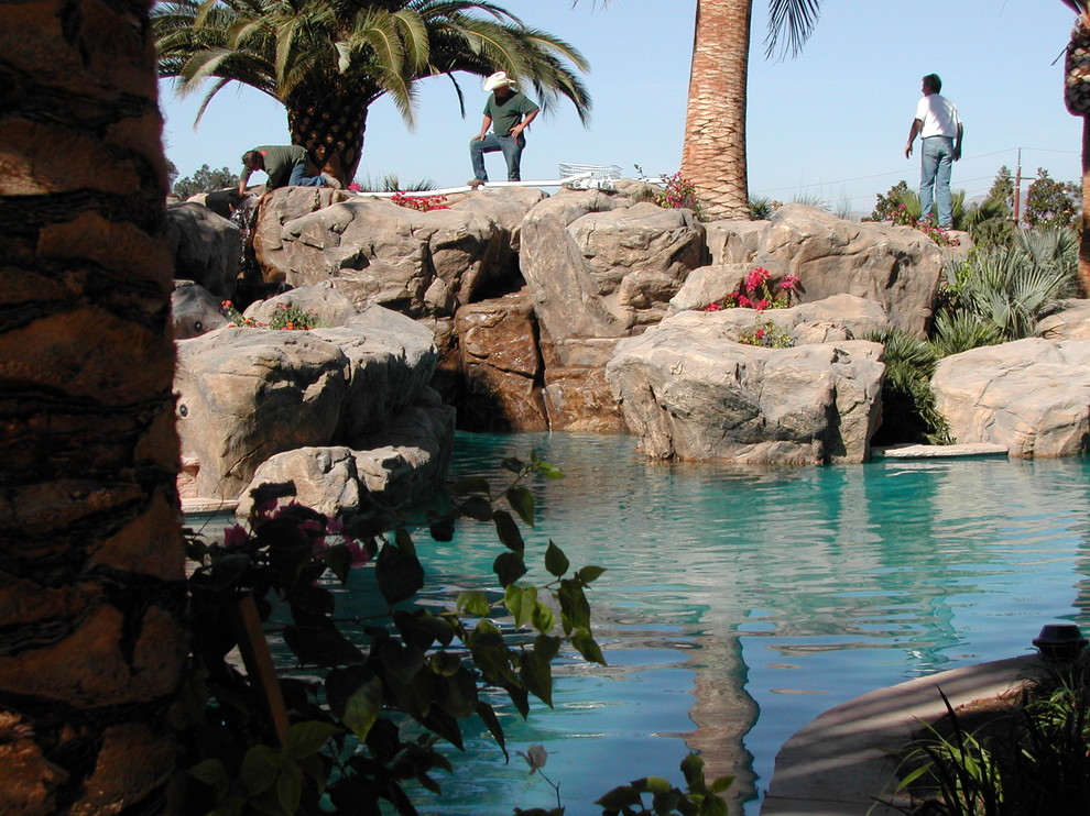 На фото: большой естественный бассейн произвольной формы на заднем дворе в морском стиле с фонтаном с